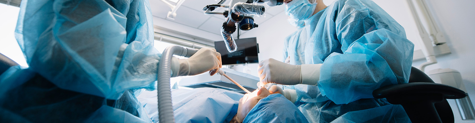 two oral surgerons performing oral surgery on patient