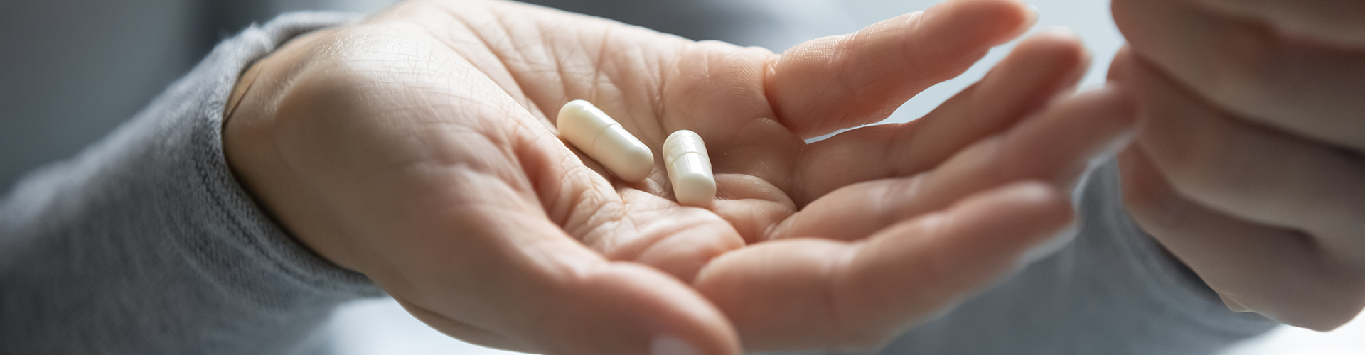 hand holding two pill capsules