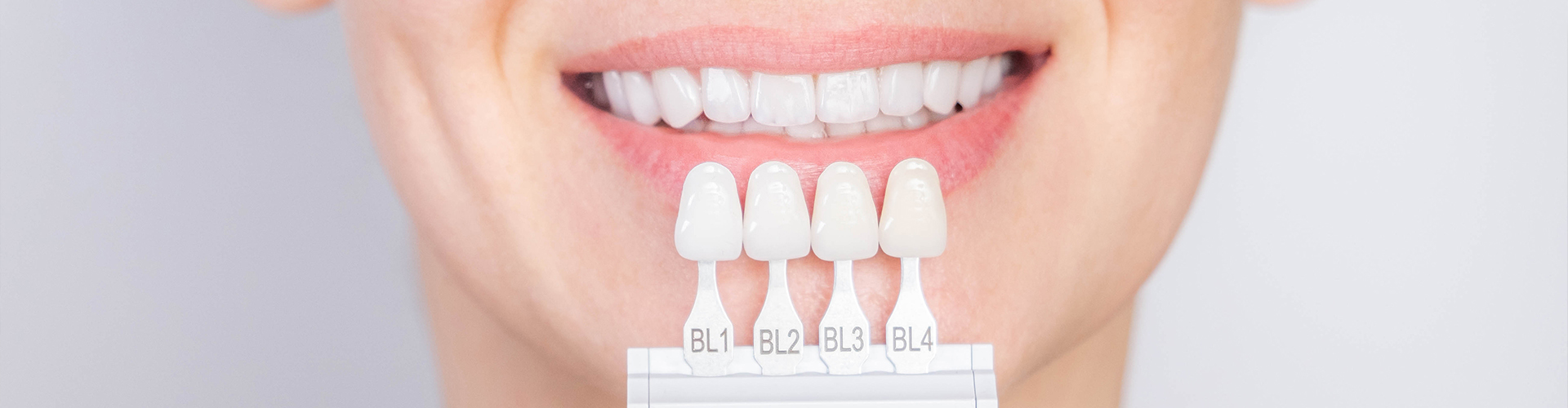 woman holding shades of dental veneers next to her smile