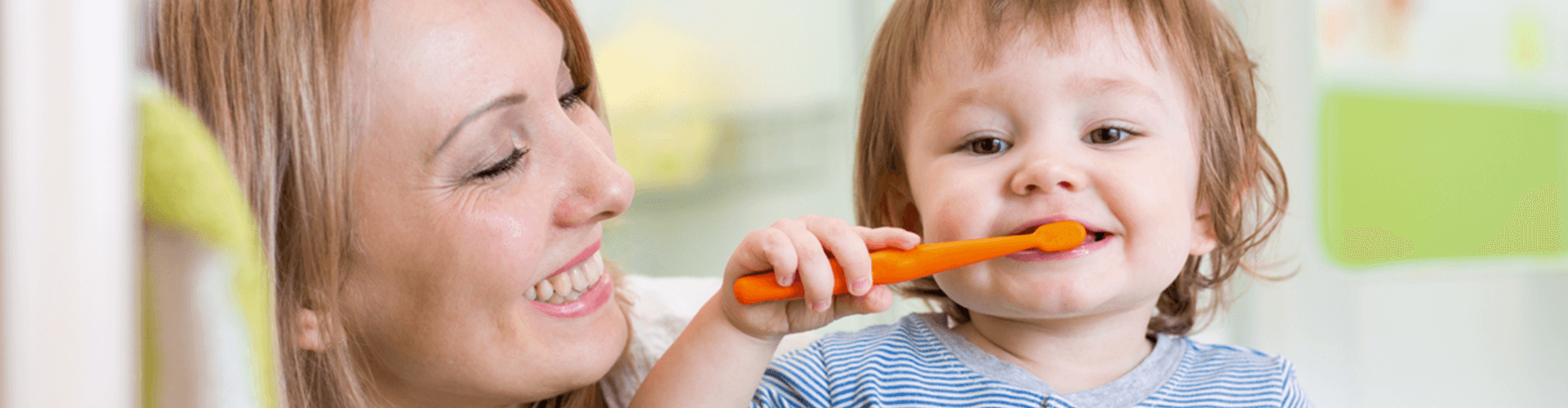 Mom helping baby brush teeth.