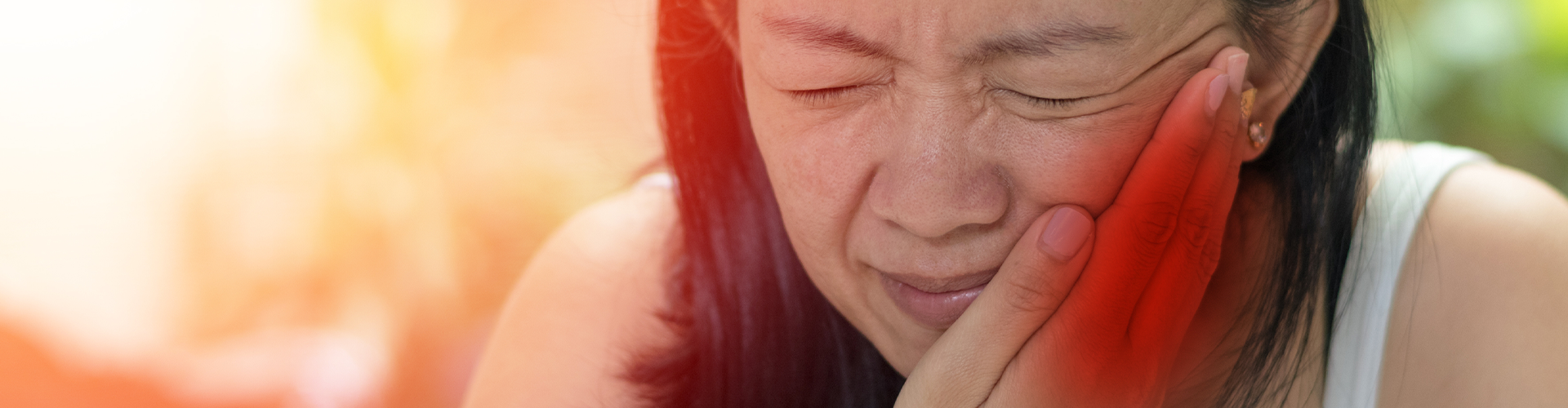 woman holding her cheek in pain