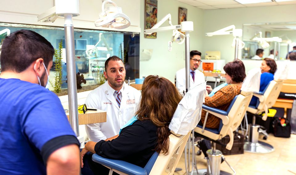 Dental treatment room with two dentists talking to their patients.