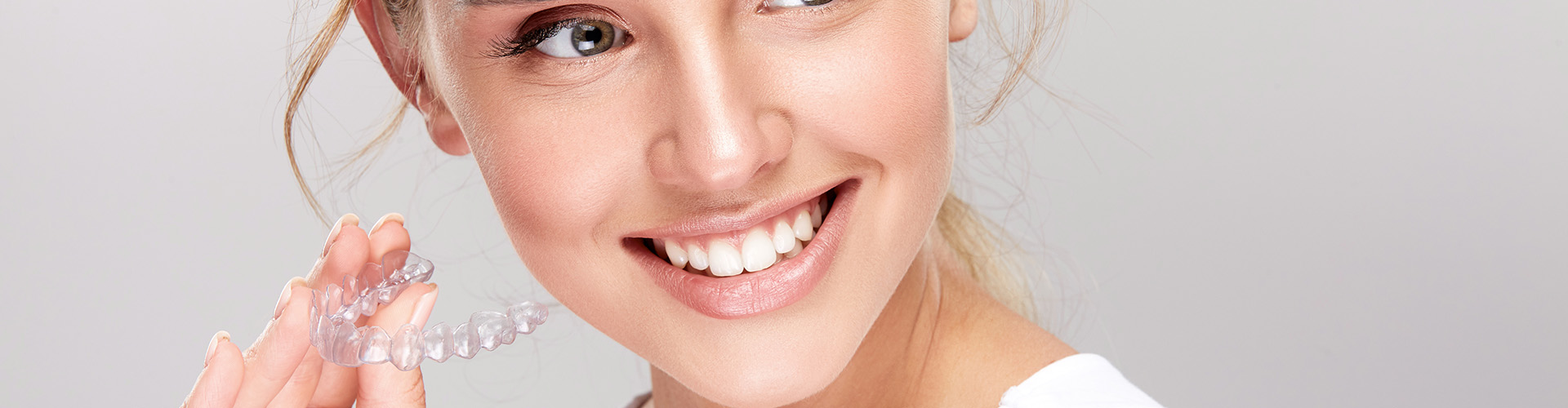 smiling woman holding clear aligner
