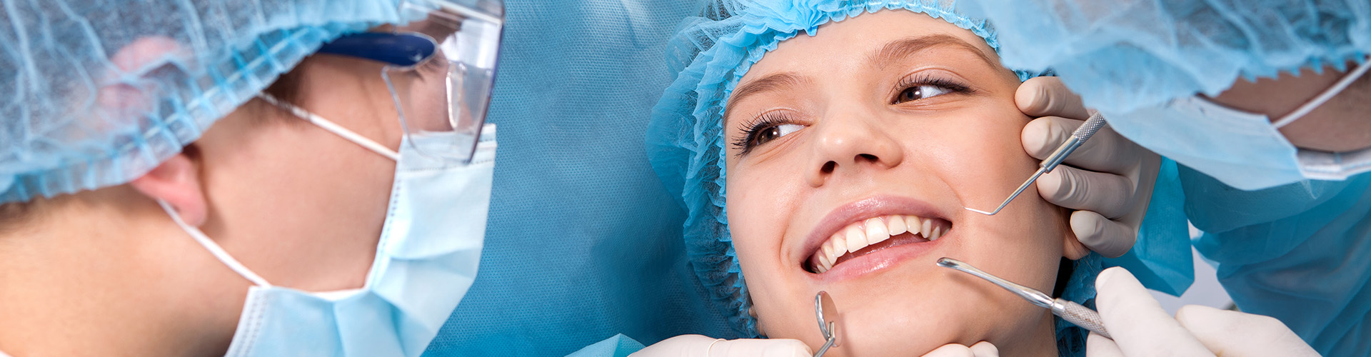 dentists holding dental tools near the mouth of smiling patient