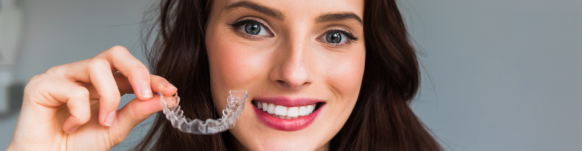 smiling woman holding clear aligner