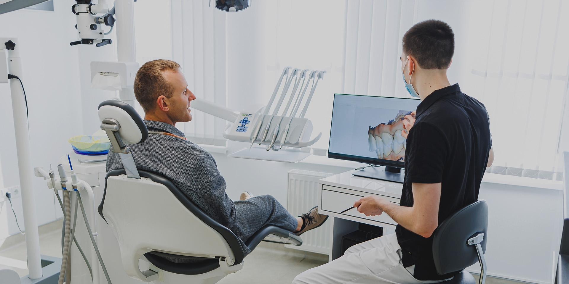 A dentist showing a patient a 3D illustration of teeth
