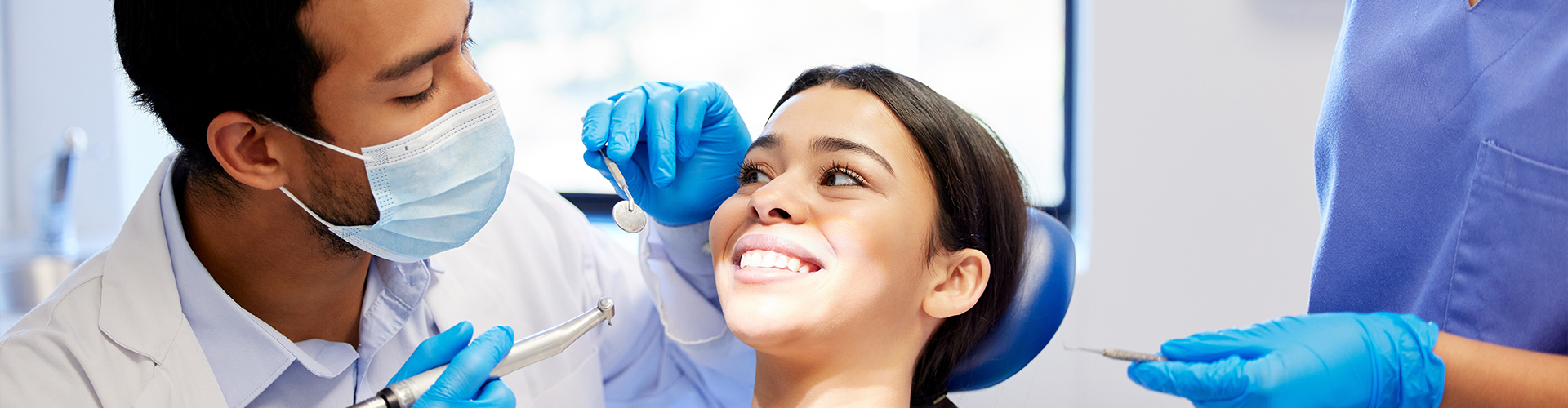 woman smiling at dentist holding dental tools