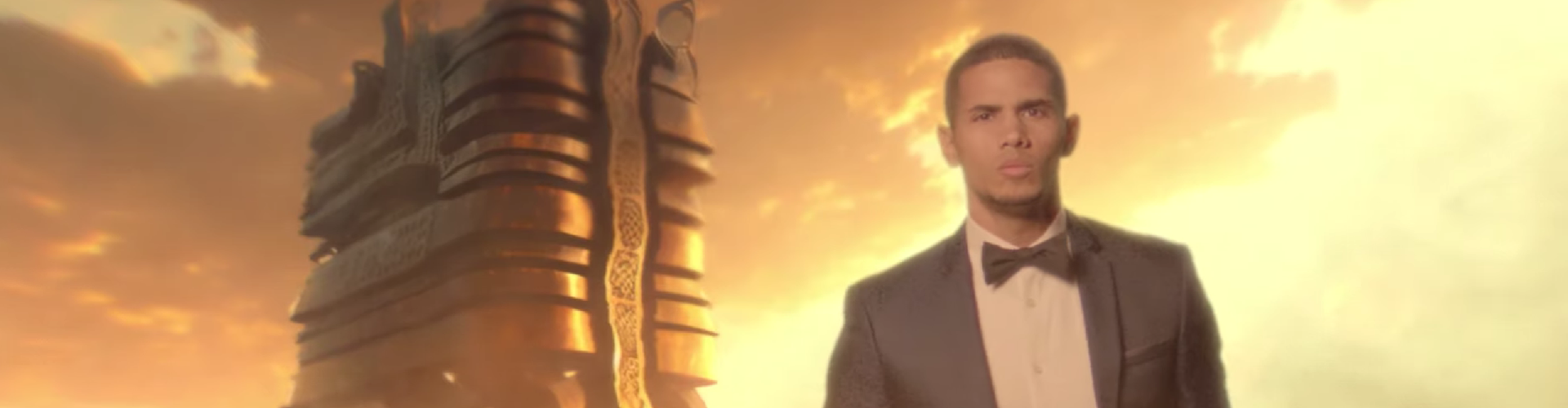 A man in a suit with a straight face walking toward the camera against a desert-like background.