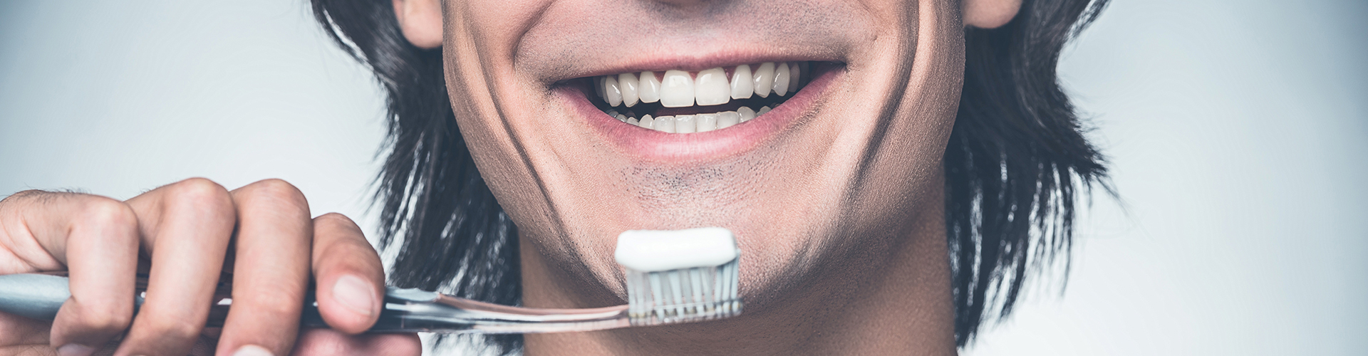 Man smiling while holding toothbrush.