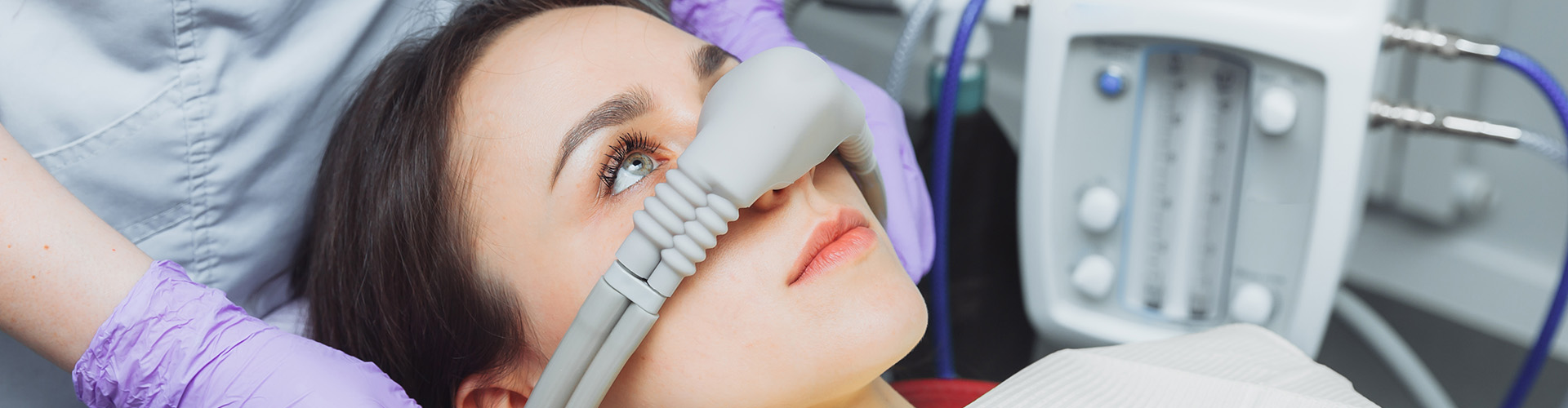 gloved hands placing sedation mask over female's face