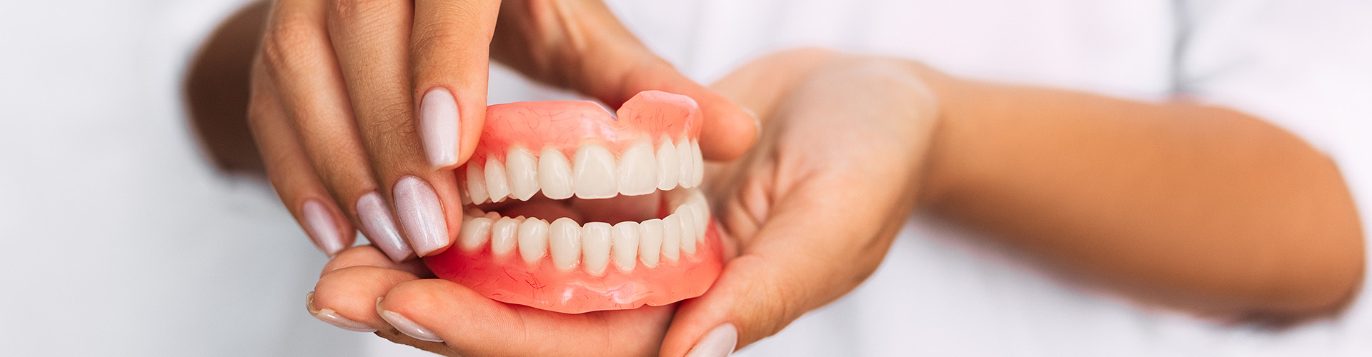 hands holding a pair of dentures