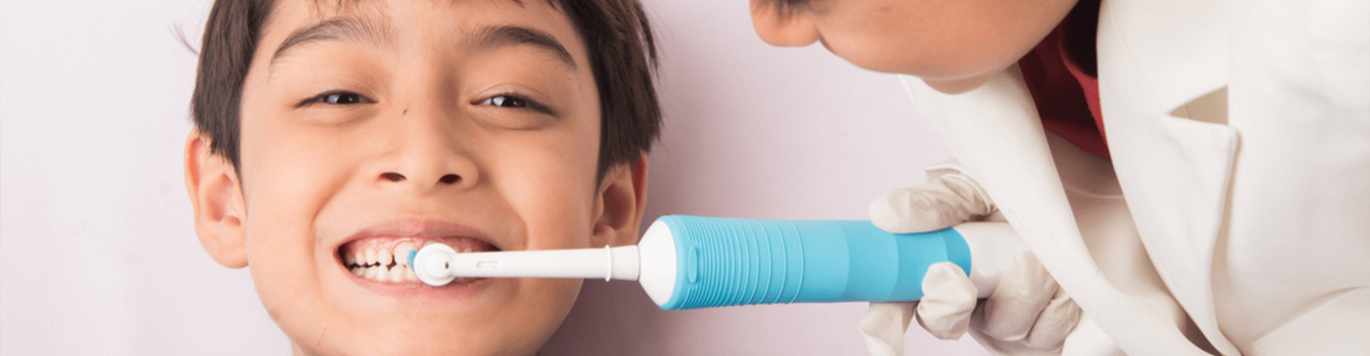 Smiling kid having his teeth brushed.