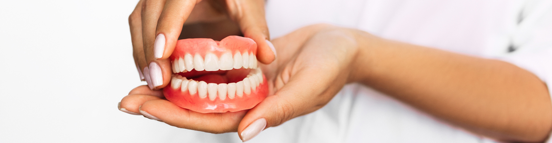 Hands holding a pair of dentures.