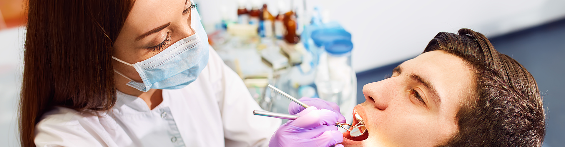 dentist working with tools in the mouth of a man in a dental chair