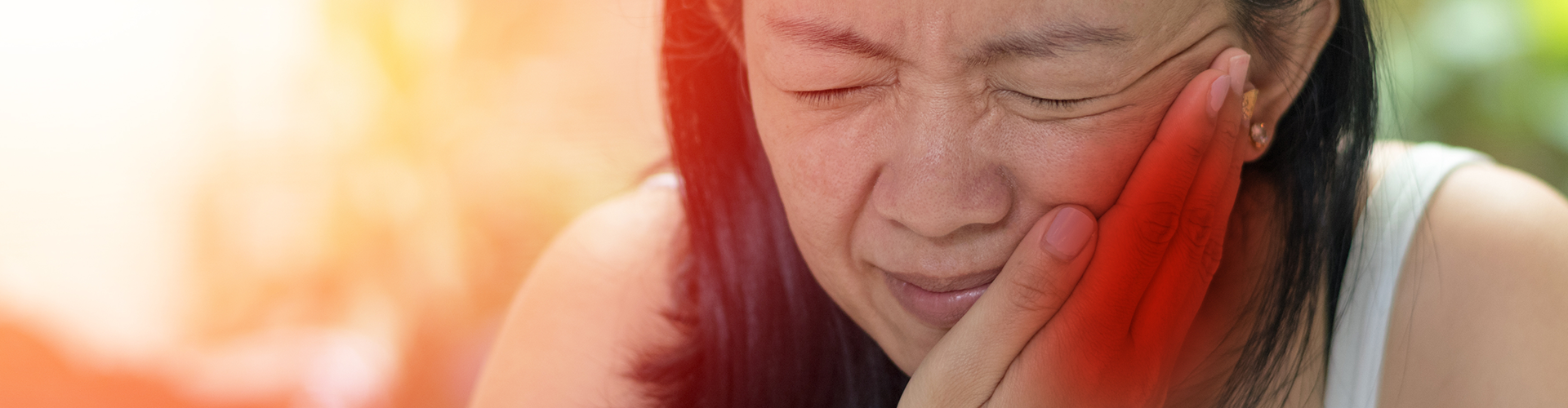 woman grimacing in pain and holding cheek