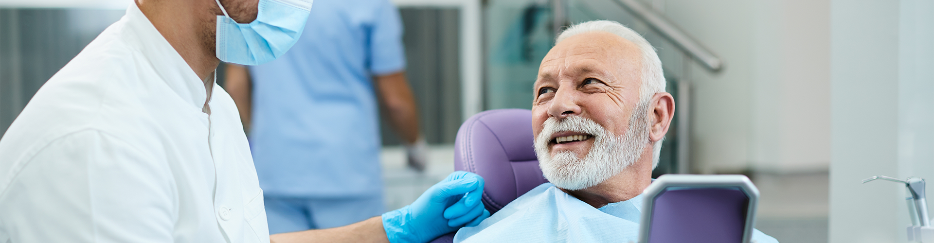 man holding mirror and smiling at dentist in mask