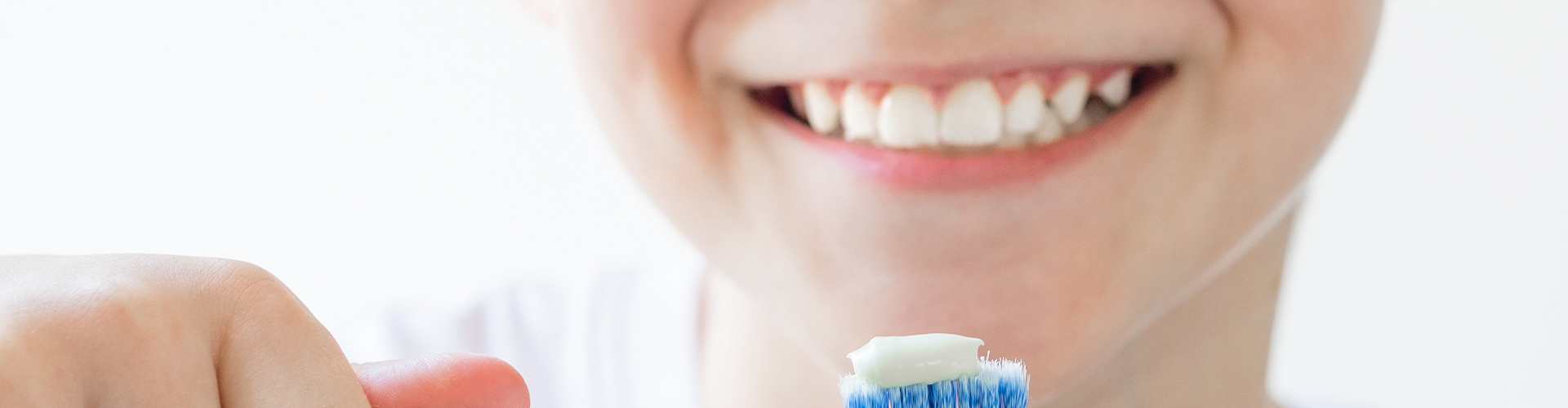 Smiling boy holding a toothbrush.