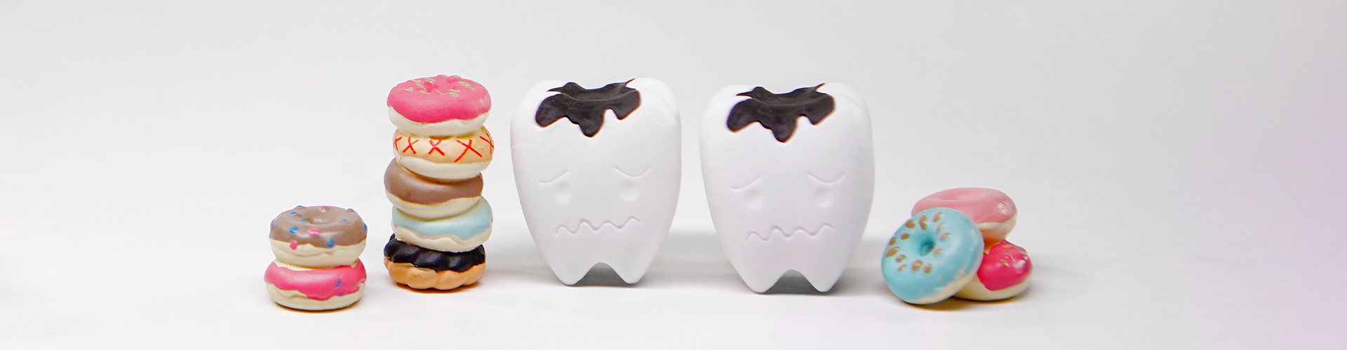 Teeth models with cavities surrounded by sweets.