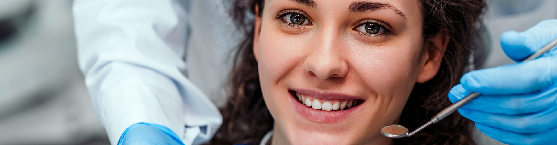 dentist holding dental tools beside smiling woman's head