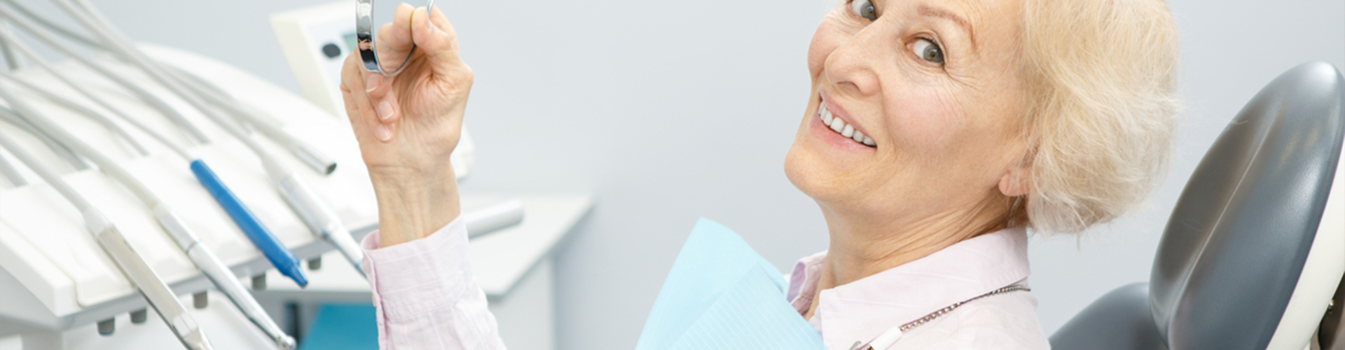woman smiling holding a mirror at the dentist office