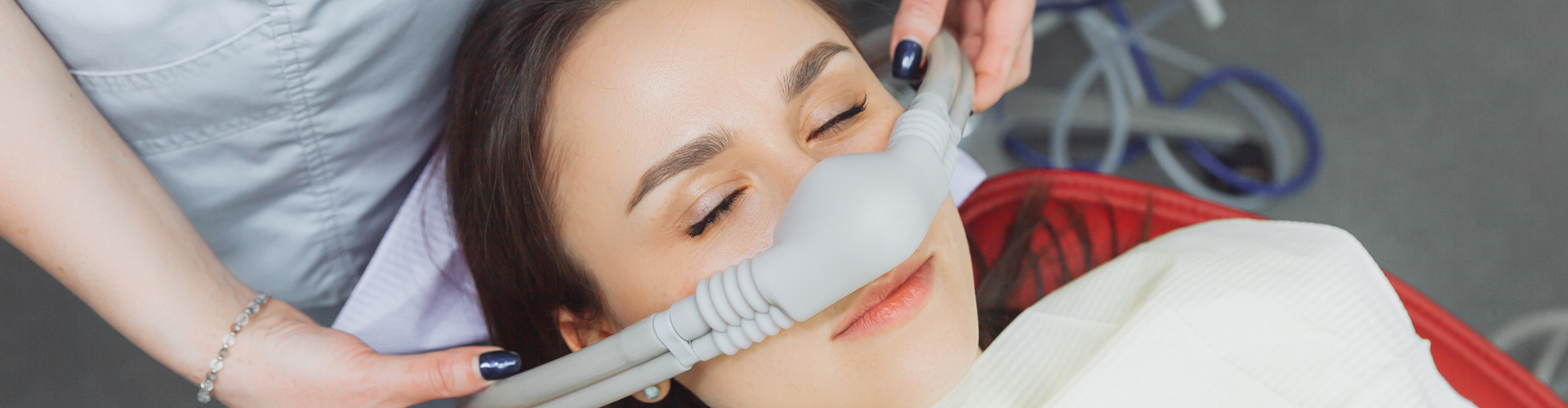 Dentist placing a breathing mask over a woman's nose.