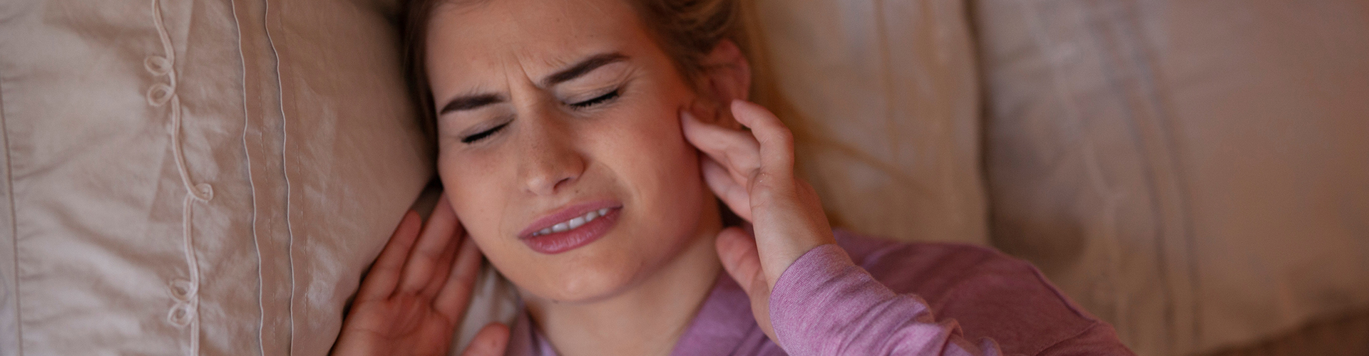 woman in bed holding her jaws in pain