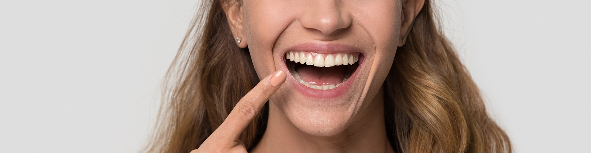 Smiling woman pointing at mouth.