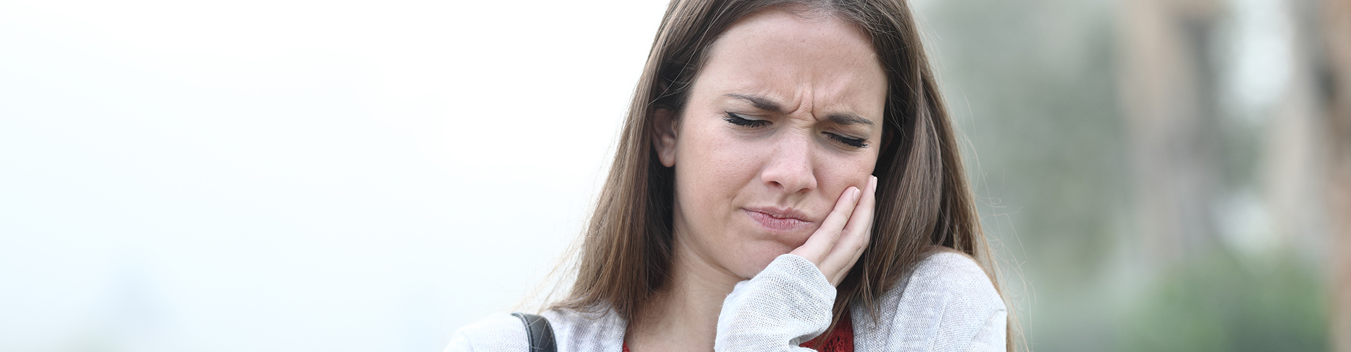 woman holding her cheek in pain