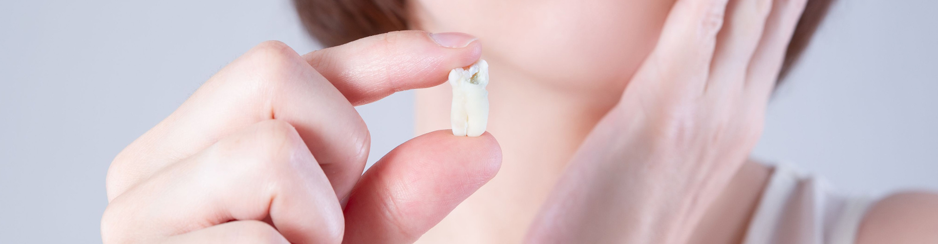 Woman holding extracted tooth.