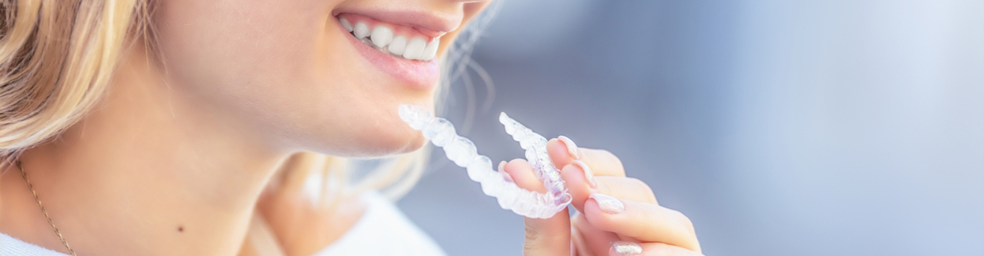 woman smiling while holding aligners