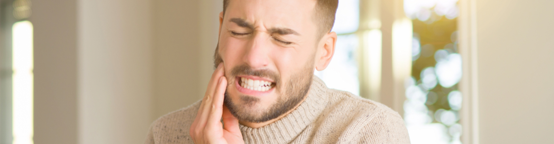 man holding cheek in pain