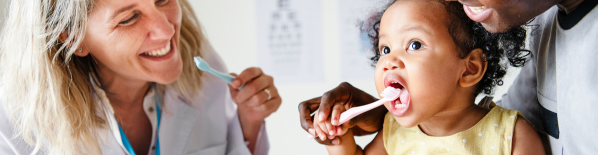 child learning to brush teeth at dentist office with parent